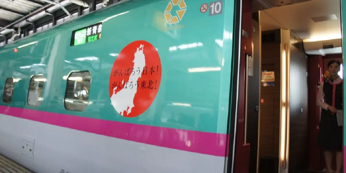 Tohoku Shinkansen Train in station with open door and attendant inside.