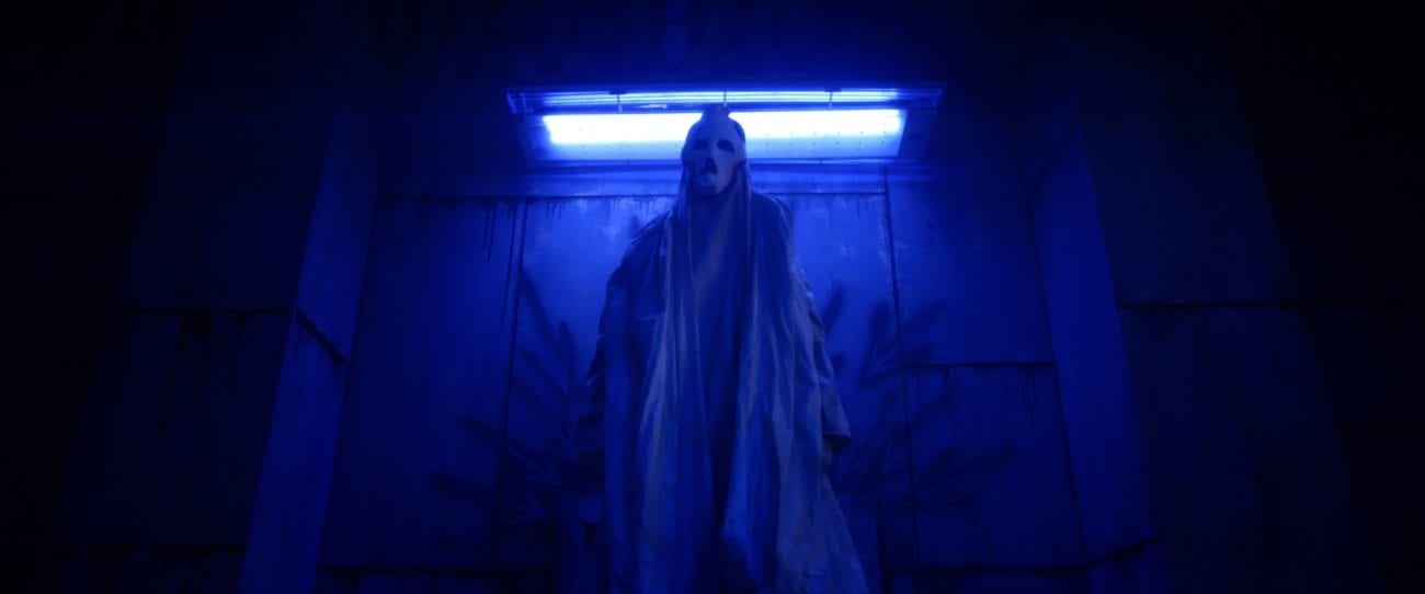 A ghostly figure from the movie Haunt stands in blue light