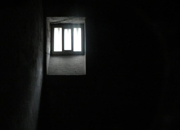 A prison cell. Completly dark except for a single window in the corner of the room that is letting in the smallest amount of light.