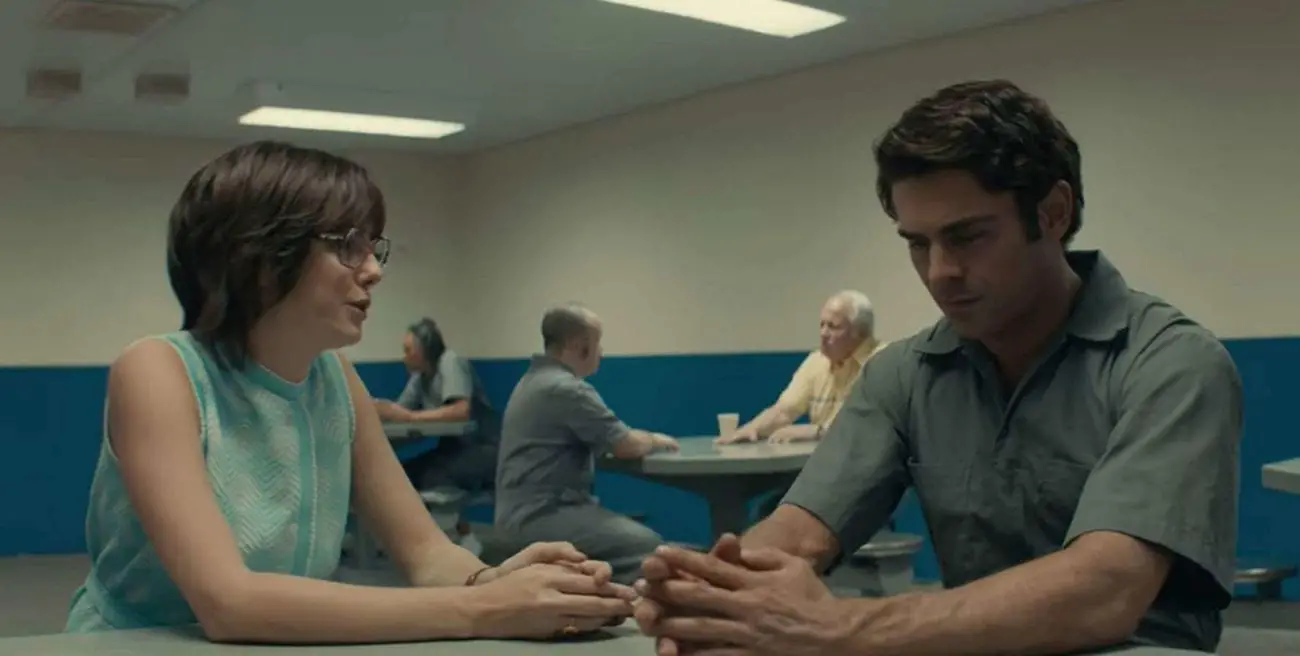 A man and a woman sit a table in a crowded room, deep in conversation.
