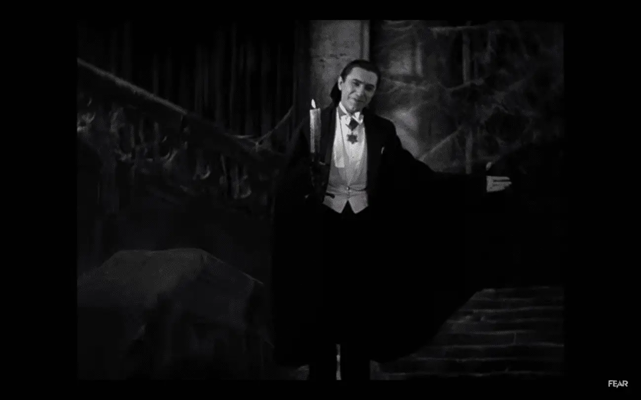 Count Dracula (Béla Lugosi) holds one arm out in a beckoning welcome and holds a candle in the other hand in the film, "Dracula" (1931).
