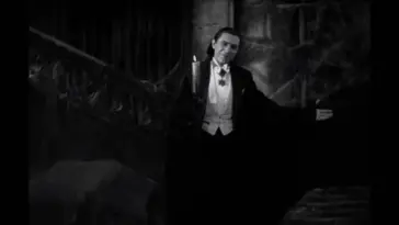 Count Dracula (Béla Lugosi) holds one arm out in a beckoning welcome and holds a candle in the other hand in the film, "Dracula" (1931).
