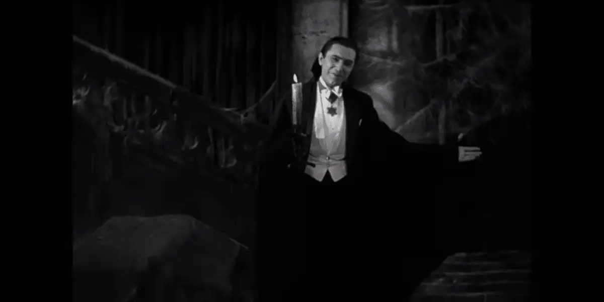 Count Dracula (Béla Lugosi) holds one arm out in a beckoning welcome and holds a candle in the other hand in the film, "Dracula" (1931).