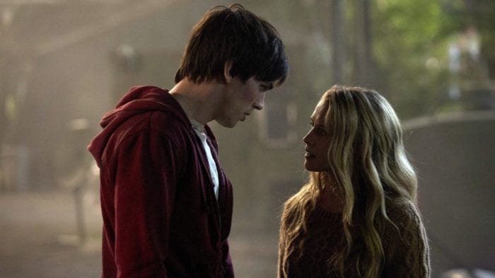 A man and woman stand close in deep, serious conversation.