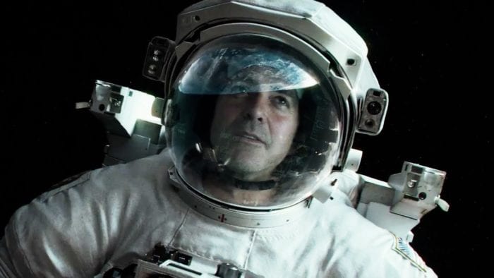 Matt Kowalski (George Clooney) floats in space in a spacesuit, the earth reflected in his visor