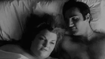 Black and white image of a man and woman laying in bed.