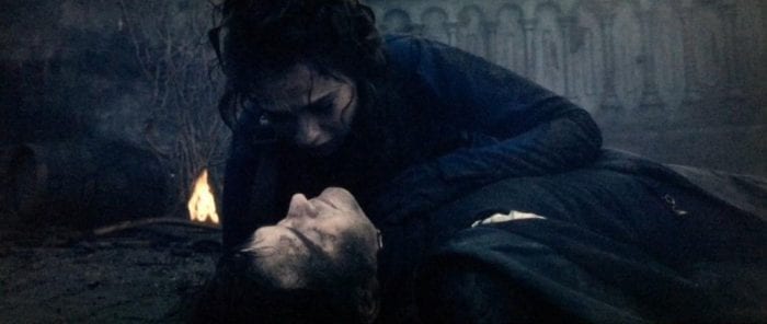 A woman leans over a man who is lying on the ground.