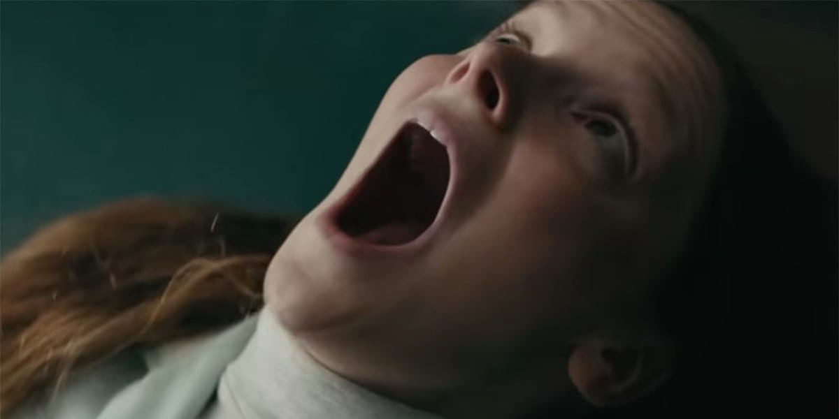 Close-up of a woman looking up with her eyes and mouth open unnaturally wide.