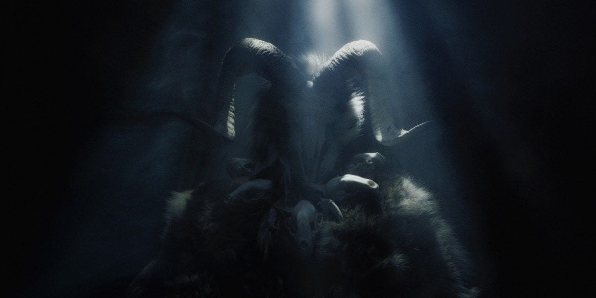 An evil creature with horns basked in rays of light in the darkness