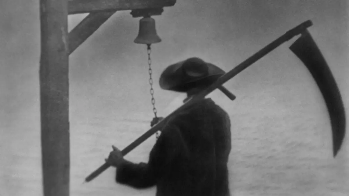 A man rings a bell while wielding a scythe.