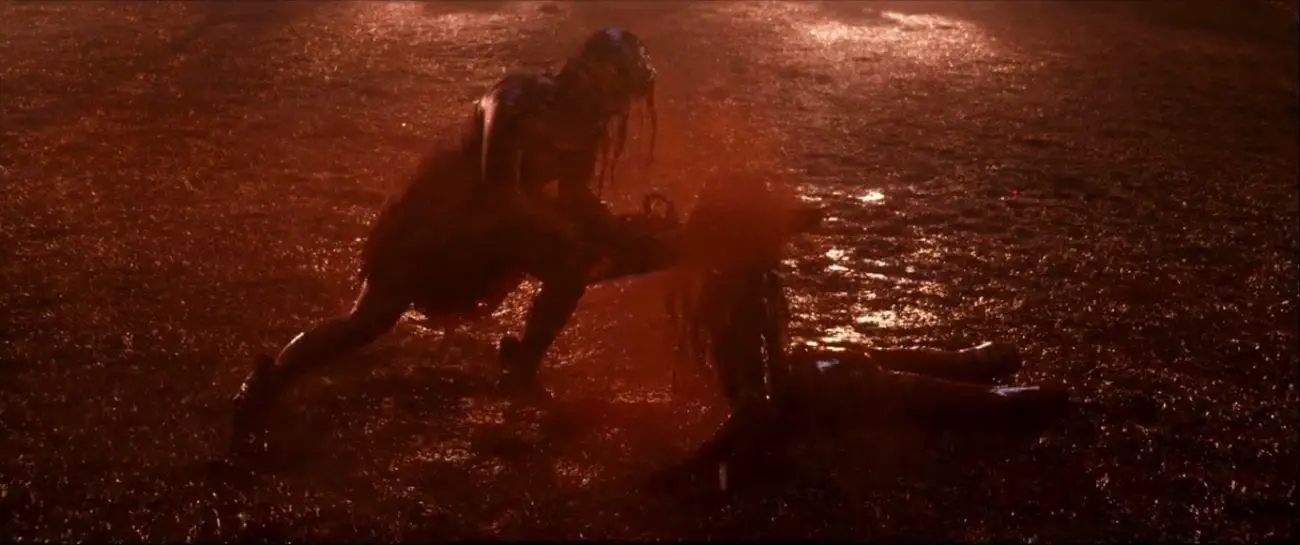 A woman covered in blood is wielding a chainsaw which she is using to cut down a demon that is crawling at her feet.
