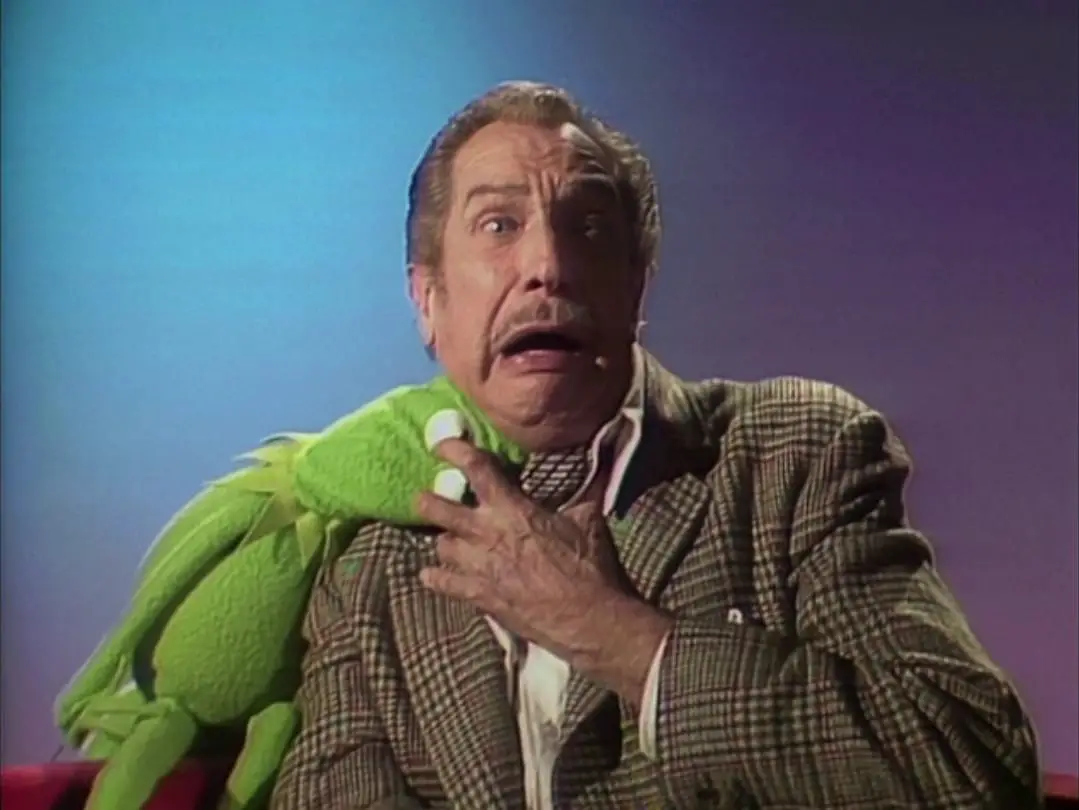 Kermit the Frog bites Vincent Price's neck vampire-style, in the TV show, "The Muppet Show."
