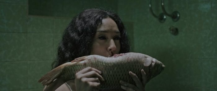 A creepy woman eating a fish