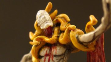 a painted figurine of a mysterious yellow clad figure