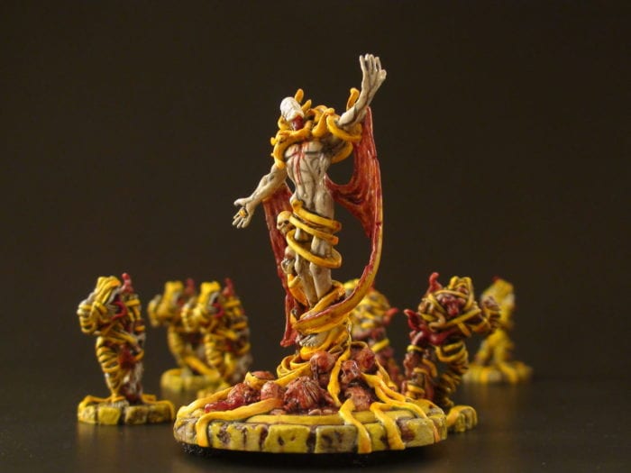 painted miniatures show a mysterious yellow clad figure surrounded by smaller cultists in yellow