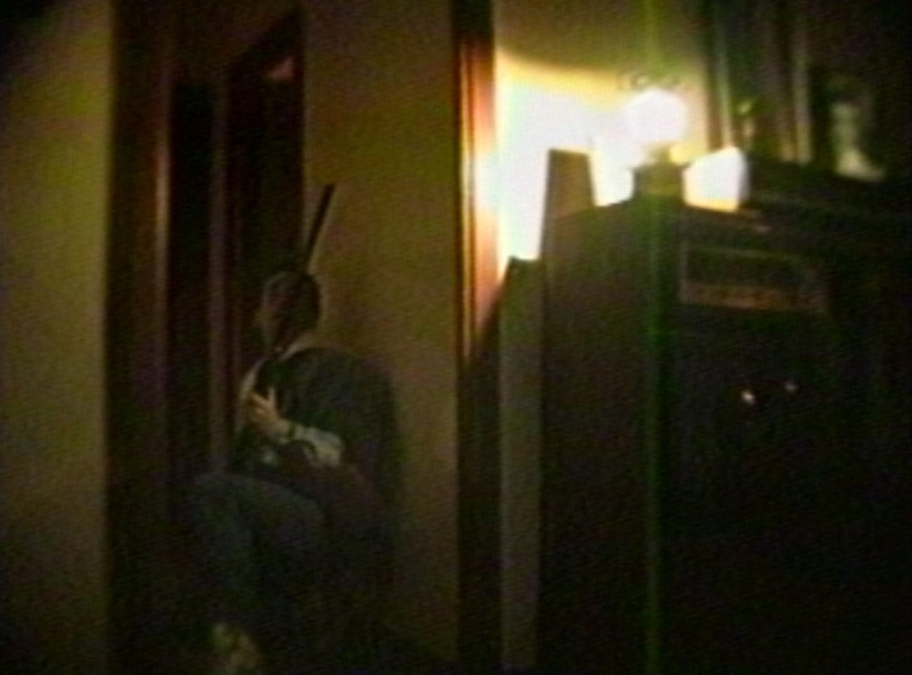a man crouched and holding a shotgun against a wall
