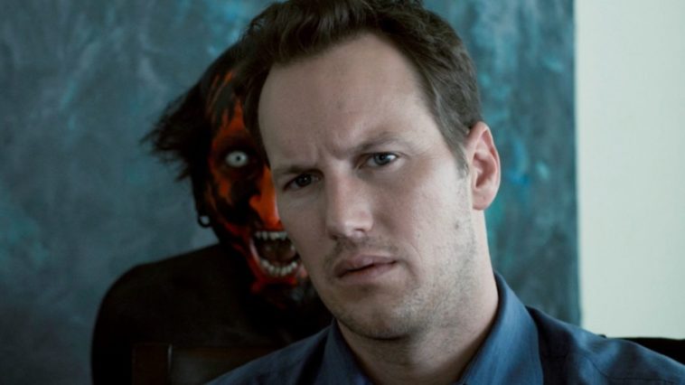 Close-up of a red-faced ghoul peering over a man's shoulder.