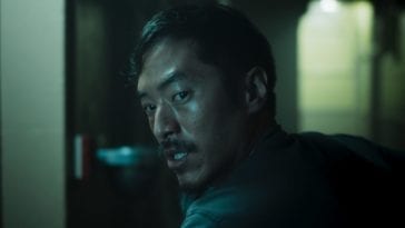 A scared Johnny (Leonard Nam) turns his head in a dark hallway to find something fearful.