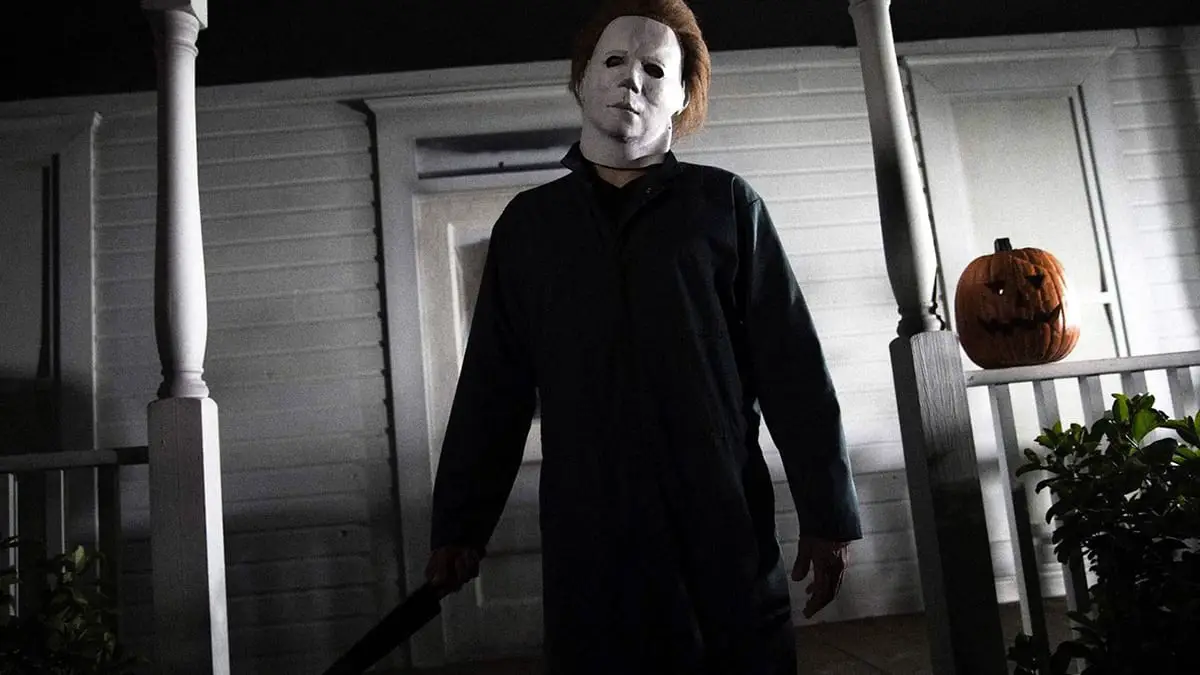 Michael Myers stands on a porch holding a knife.