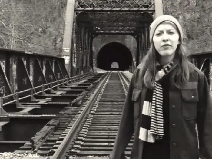 Sophia stands in front of a train trestle and tunnel