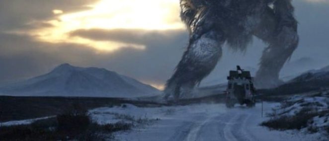 a jeep on a snowy road sits in front of a giant troll, many times larger than it