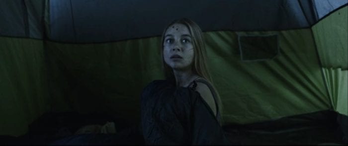 Jen sits up encased in her sleeping bag inside of a tent