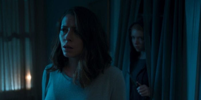 Emma (Lauren Miller Rogen) is standing in her room, oblivious to there being a murderous teenager behind her.
