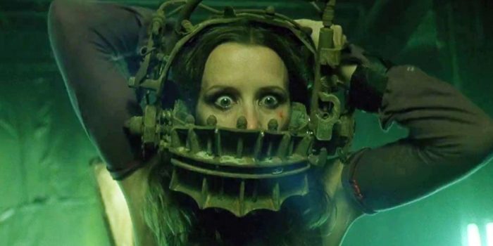 Close up of wide-eyed woman struggling with torturous device clamped around her head in Saw.