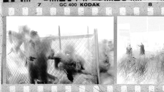 A film negative shows several people rushing towards the camera, their images distorted