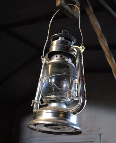 An antique lantern hangs from a hook in a cabin