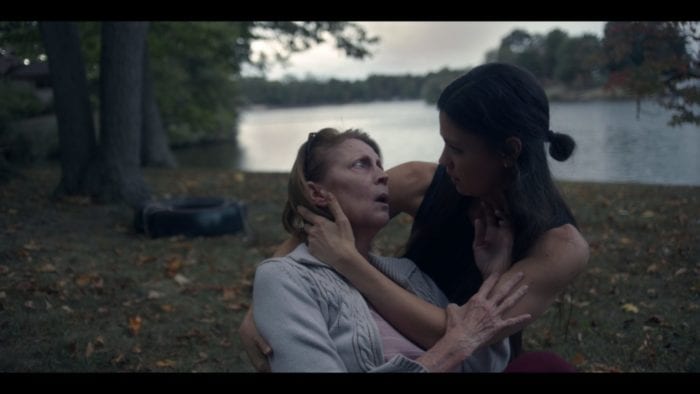A young woman holds an older woman by a lake in She Watches from the Woods
