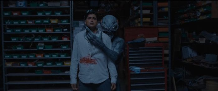 Luis' head is being held threateningly by the Alien standing behind him 