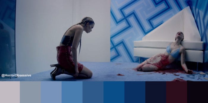 Sarah kneels on a carpet and stares at Gigi, dead and covered in blood
