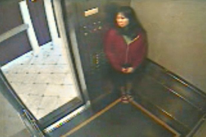 In this image Elisa Lam is seen hiding in the elevator wearing a red sweater and a black skirt. 