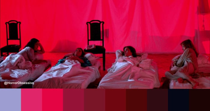 four girls in beds chat amongst themselves. the room is lit brightly red