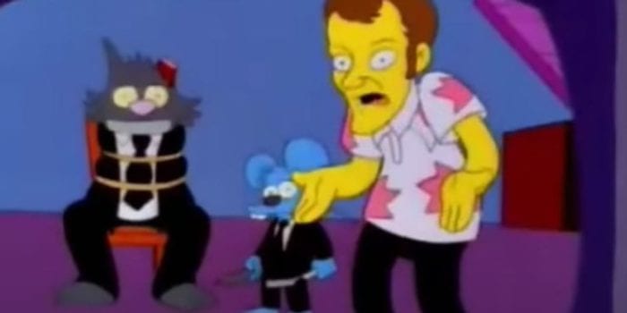 In the background, an animated cat tied to chair and missing an ear, next to him is an animated mouse holding a straight razor. In the foreground, a bug-eyed, animated version of Quentin Tarantino, mouth open in mid-sentence, holds his hands out, palms up.