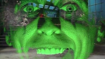 Alice Cooper's face, lit up green, is superimposed over a dungeon, in the TV show, "The Muppet Show."