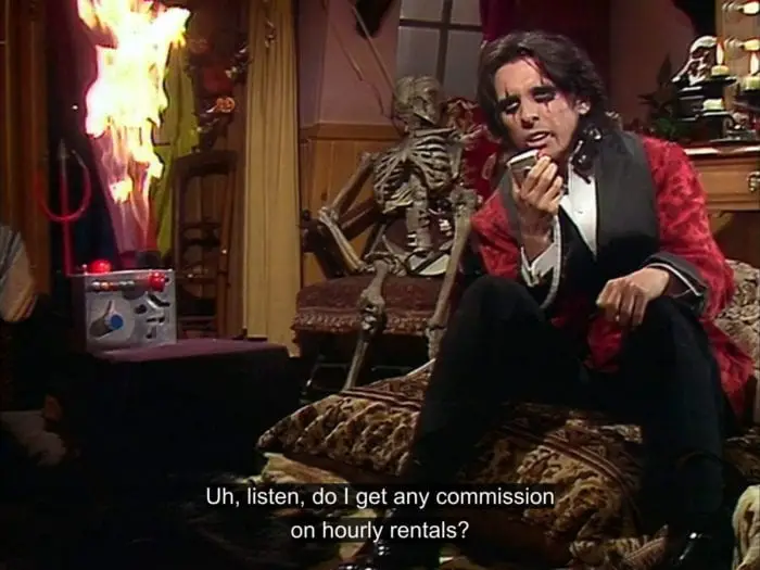Alice Cooper talks into a speaker, saying, "Uh, listen, do I get any commission on hourly rentals?", while the device near the speaker is on fire, in the TV show, "The Muppet Show."