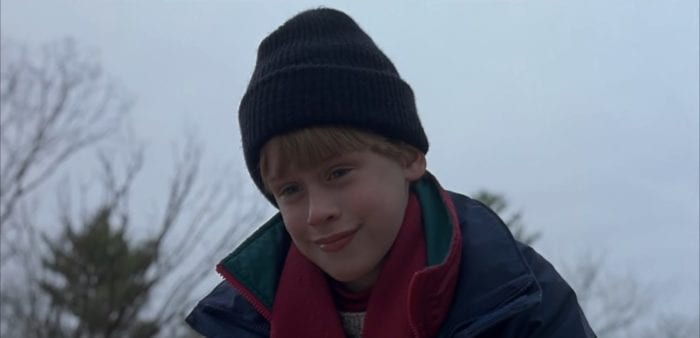 Macaulay Culkin smiles smugly while wearing a winter hat outside.