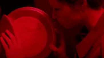 A woman examines a film reel in a red lit room