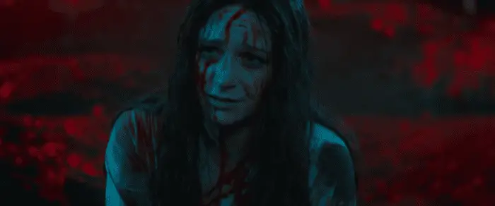 A woman covered in blood in a red-lit forest in Censor