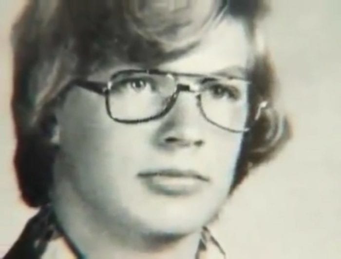 A face shot of a blonde teenage boy wearing glasses.