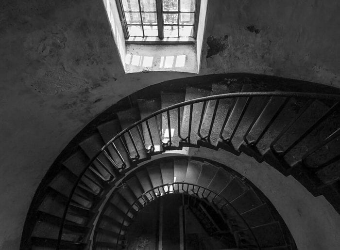 A winding staircase goes down into the darkness below