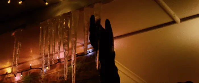 A gloved hand reaches for an icicle.