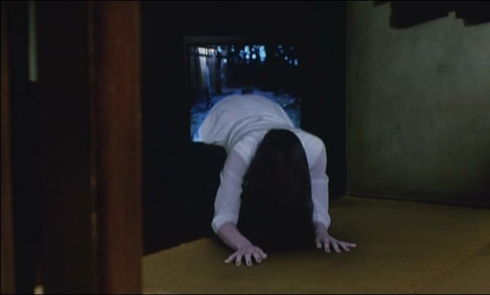 A woman in a white dress with long, black hair crawls out of a TV screen.
