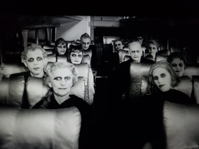 Ghoulish, ghostly entities with disturbing white faces crowd a bus