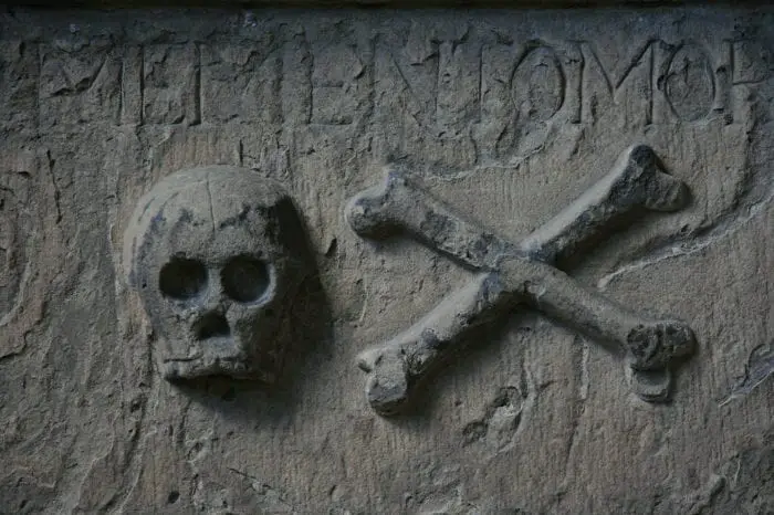 A skull and crossbones carved into a grey stone surface.