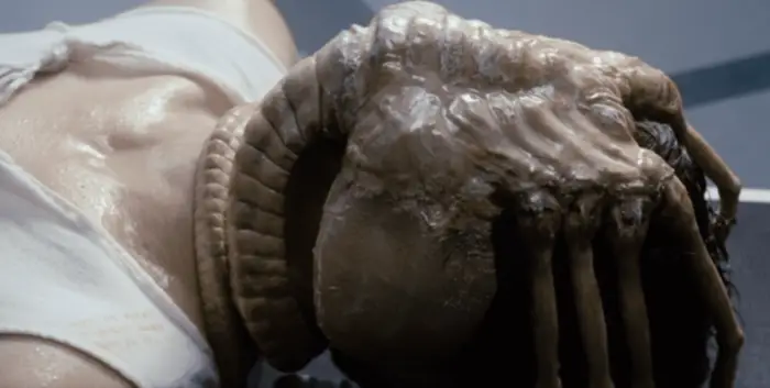 A facehugger clings to a crew member's face