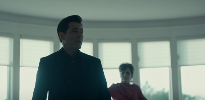 Luke stands in a white room with windows and another real estate agent behind him