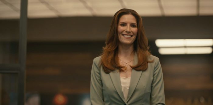 Susan stands in the doorway of the boardroom of the Roman Agency smiling wearing a seafoam green pantsuit.